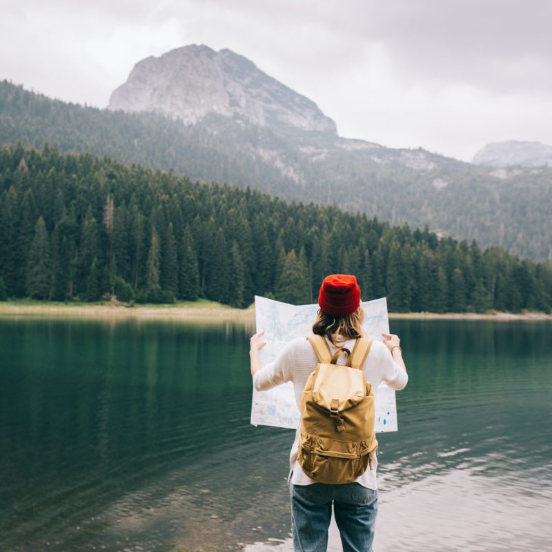 Travel woman with backpack checks map