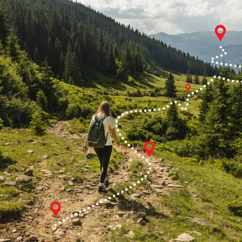 Woman traveler explorer with backpack hiking to the top of the mountain. Adventure weekend concept.